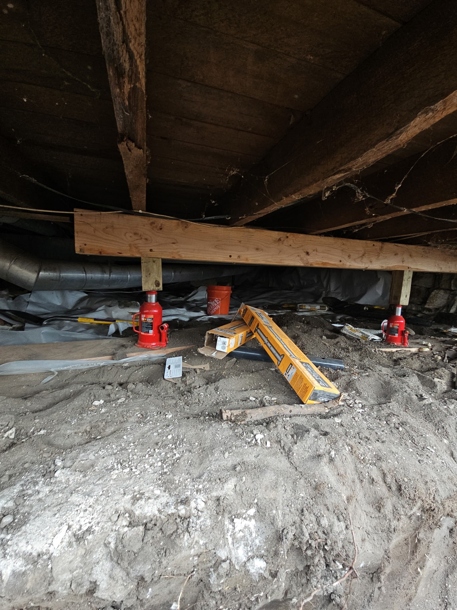 Sagging crawlspace beam with hydraulic jacks before repair — Ankeny, IA