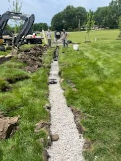 Excavator installing a French drain with gravel bed in Eudora, KS