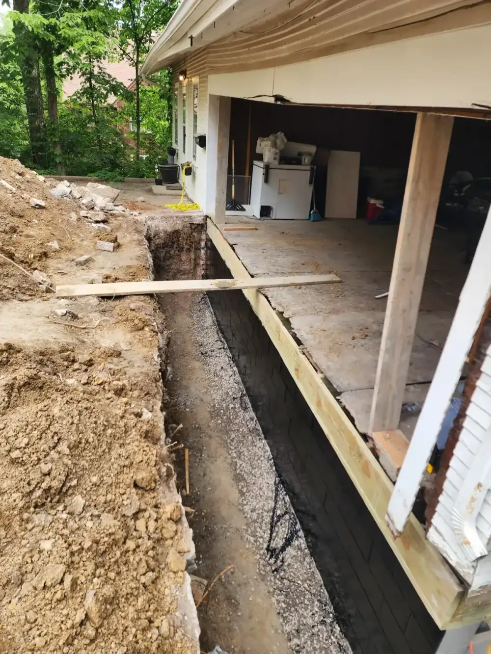 Foundation repair crew places concrete footing at the bottom of an excavated trench in Kansas City
